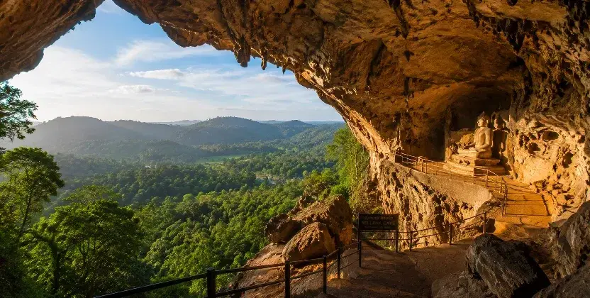Belilena Cave overlooking a lush green valley with a Buddha statue.