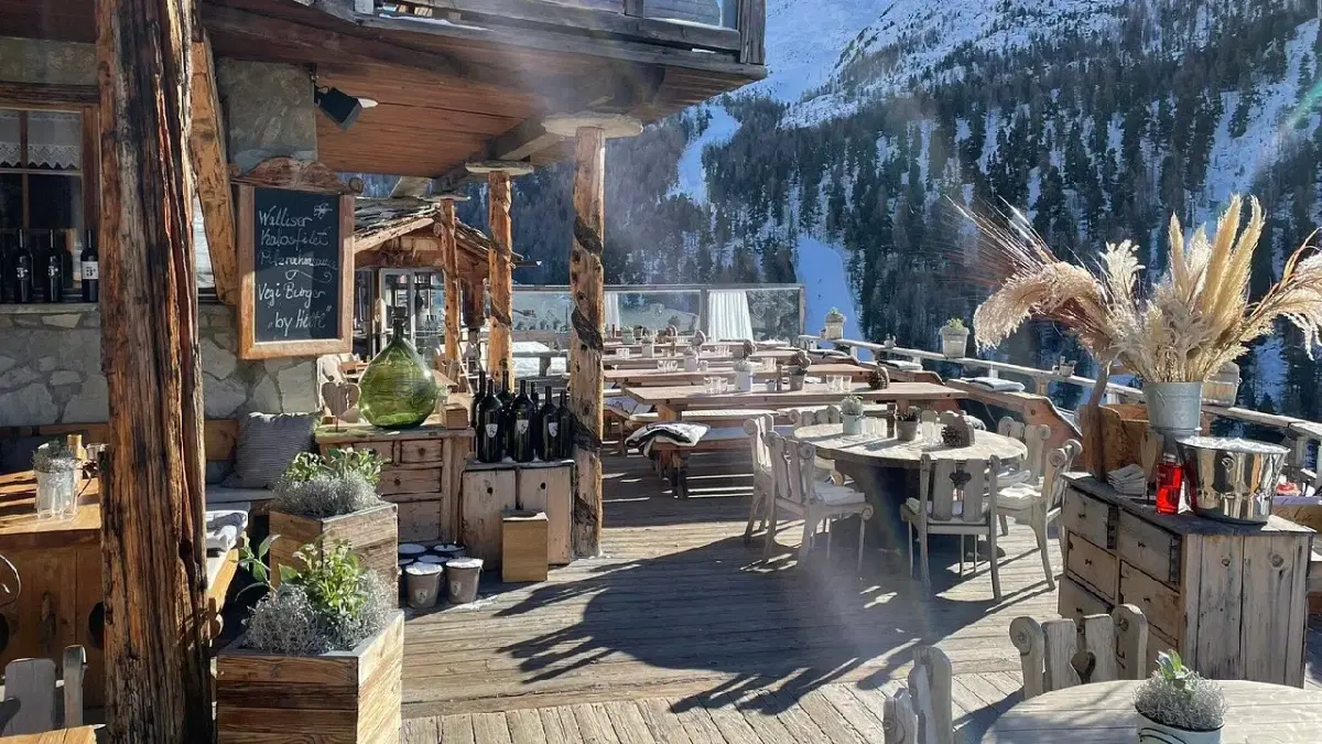 View of Chev vrony Mountain top restaurant with the swiss alps and trees behind 