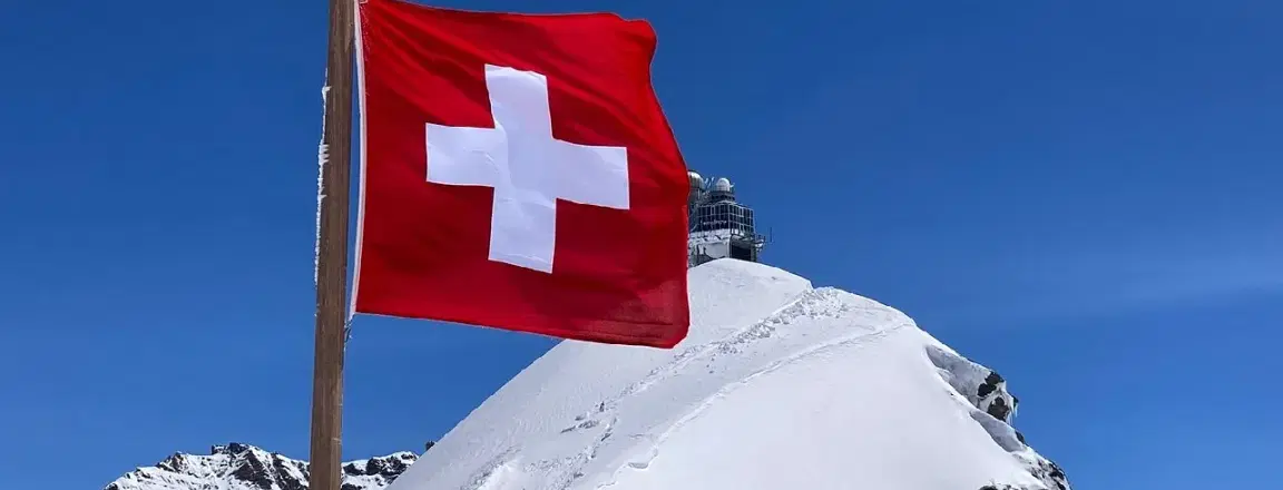 Swiss flag waving in-front of Alpine ranges in Jungfraujoch