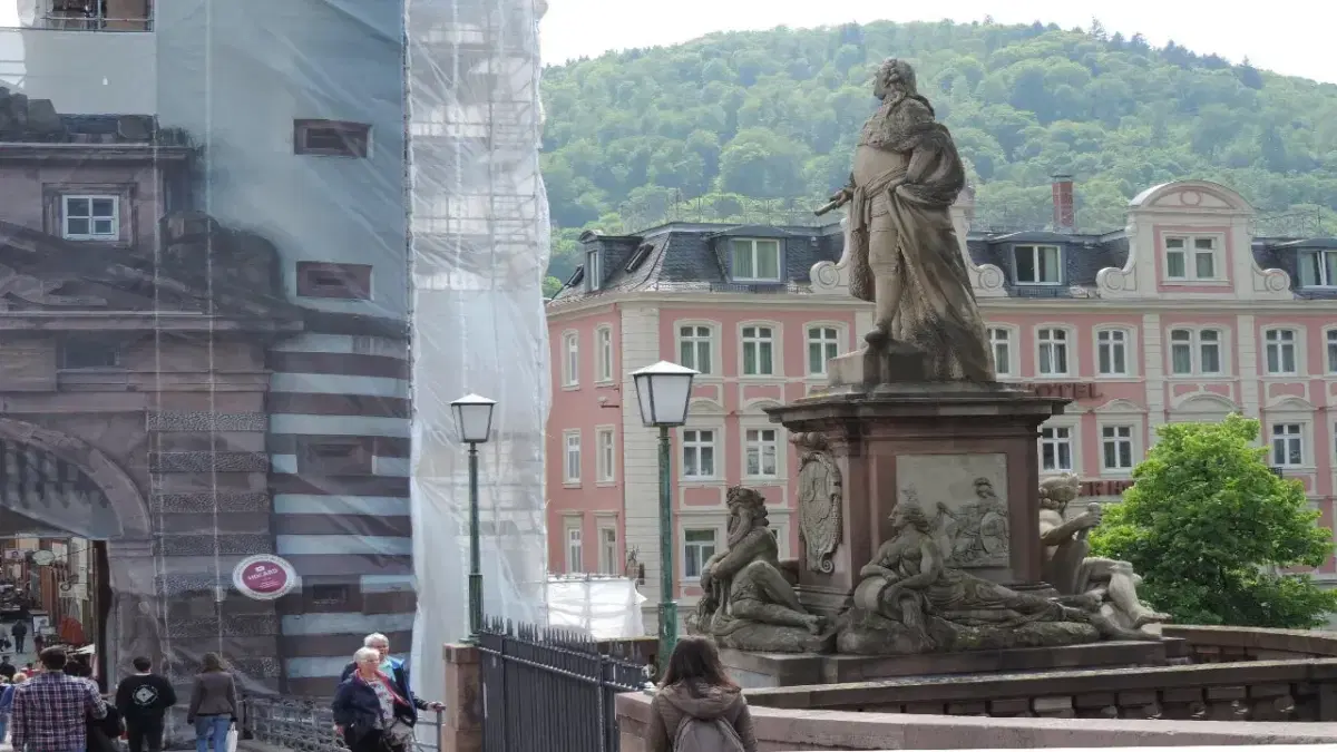 View of Altstadt (Old Town) with people passing a statute in the street
