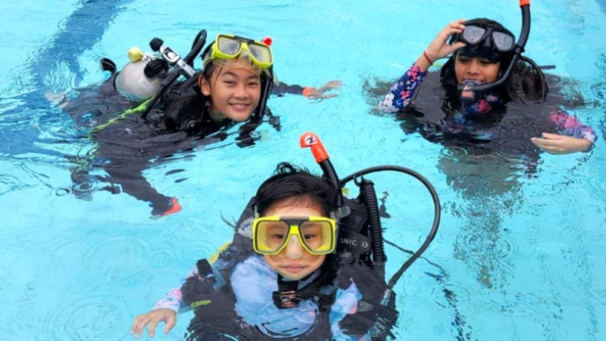 Children learning scuba diving in a swimming pool during a diving course in Singapore